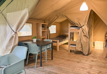 Interno di una tenda safari all'Hvalpsund Familie Camping in Danimarca con letti a castello e tavolo.