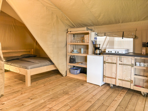 Vista interna di una tenda safari a Hvalpsund Familie Camping, Danimarca, con letto e cucina attrezzata.