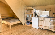 Interior view of a Safaritent at Hvalpsund Familie Camping in Denmark, with bed and equipped kitchen area.