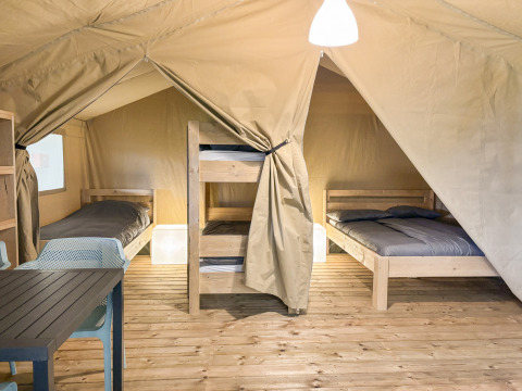 Interior of a Safaritent at Hvalpsund Familie Camping in Denmark featuring beds, bunks, and table.