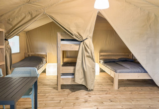 Interno di una tenda safari all'Hvalpsund Familie Camping in Danimarca con letti, cuccette e tavolo.
