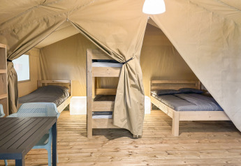 Interior of a Safaritent at Hvalpsund Familie Camping in Denmark featuring beds, bunks, and table.