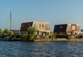 Dos cabañas modernas junto al lago con terraza y barco, ideales para glamping bajo cielos despejados.