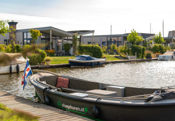 Foto di un moderno lodge sul canale con piccole barche e tanto verde in una giornata di sole.