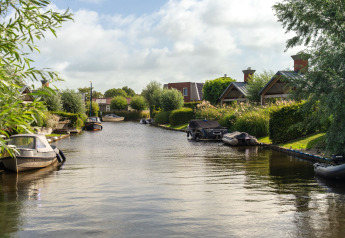 Idyllisk udsigt over en vandvej ved et lodge, omgivet af grønne træer, både og hyggelige hytter.