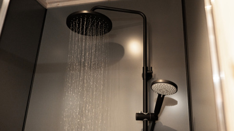 Moderne Dusche in einer Lodge mit großem Regenduschkopf und Handbrause in stilvollem, dunklem Badezimmer.