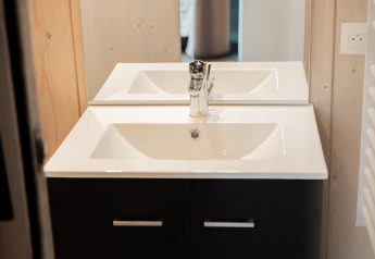 Modernes Waschbecken mit Spiegel in einem Lodge-Badezimmer, schwarz-weißes Design und Holzverkleidung.