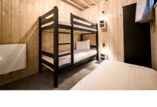Room with bunk bed and single bed at Ecolodge, featuring wood-paneled walls and minimalist decor in Belgium.