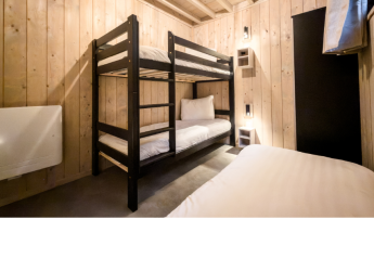 Kamer met stapelbed en eenpersoonsbed in Ecolodge, houten wanden en minimalistisch interieur in België.