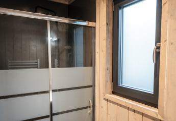 Bathroom with glass shower and wooden-framed window at Ecolodge, Hameau de la Semois, Belgium.