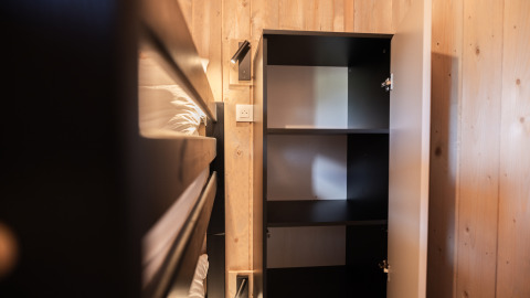 Interieur van Ecolodge tiny house in Hameau de l'Ourthe, België met stapelbed en open kast.