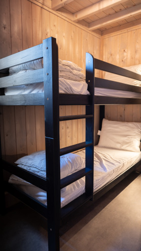 Slaapkamer met houten stapelbed in Ecolodge tiny house, Hameau de l'Ourthe, België, houten muren zichtbaar.