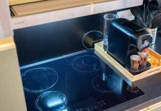Kleine Küchenecke mit Induktionskochfeld und Kaffeemaschine im Ecolodge beim Hameau de l'Ourthe, Belgien.