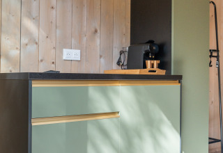 Kleine Küchenzeile mit grünen Schränken und Kaffeemaschine in der Ecolodge, Hameau de l'Ourthe, Belgien.