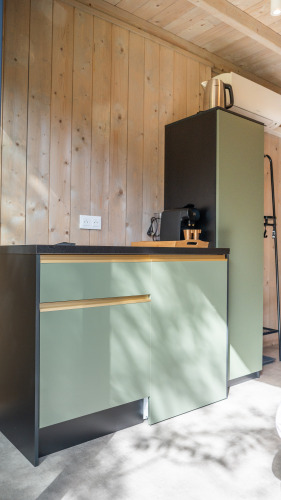 Kleine kitchenette met groene kasten en koffiemachine in Ecolodge, Hameau de l'Ourthe, België.