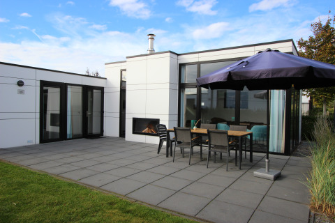 Moderne lodge L-Cube 6 ved Schoneveld i Holland med stor terrasse, udendørs pejs og spiseområde.