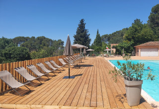 Piscina con lettini e ombrelloni circondata dal verde al Camping d'Aix en Provence, Provenza, Francia.