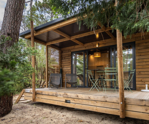 A cozy wooden cabin with a covered terrace and outdoor seating at Camping d'Aix en Provence, France.