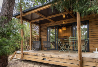 Cabane en bois avec terrasse couverte et mobilier extérieur au Camping d'Aix en Provence, en France.