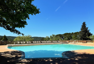 Zicht op het zwembad bij Camping d'Aix en Provence, met ligstoelen en een bosrijke achtergrond in Frankrijk.