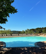 Blick auf den Pool im Camping d'Aix en Provence mit Liegestühlen und grüner Landschaft in Südfrankreich.