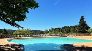 Uitzicht op het zwembad bij Camping d'Aix en Provence, met ligstoelen en groene heuvels in Frankrijk.
