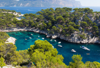 Boote treiben im türkisfarbenen Wasser einer von Pinien umgebenen Bucht nahe Aix-en-Provence, Frankreich.
