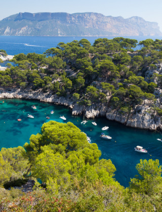 Bootjes drijven op turquoise water in een schilderachtige baai omringd door dennen nabij Aix-en-Provence, Frankrijk.