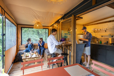 Cuatro personas se relajan en una cabaña moderna llamada Arizona, con cocina abierta y vistas al exterior.