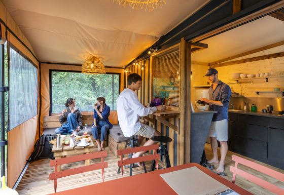 Cuatro personas se relajan en una cabaña moderna llamada Arizona, con cocina abierta y vistas al exterior.