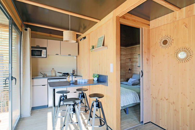 Moderno chalet Victoria in legno al Camping d'Aix en Provence, con cucina, sgabelli e camera da letto accogliente.
