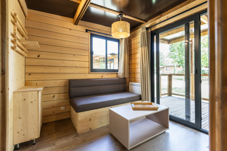 Vista interna del Victoria Chalet al Camping d'Aix en Provence, Francia, con pareti in legno e terrazza.