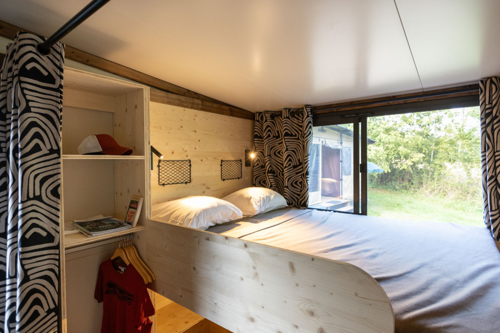 Interieur van de Arizona hut bij Camping d'Aix en Provence, met een bed, open kast en groot raam.
