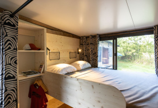 Vista del interior de la cabaña Arizona en Camping d'Aix en Provence, con cama doble y gran ventana.