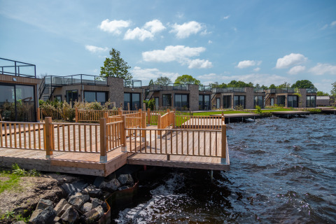Modern lakeside lodges and wooden deck at Vakantiepark De Wiedense Meren in the Netherlands in summer.