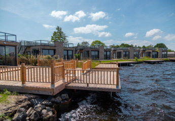 Udsigt over moderne ferieboliger og træterrasse ved en sø i Vakantiepark De Wiedense Meren, Holland.