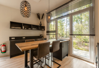 Modernes, gemütliches Tiny-House-Kücheninterieur mit großen Fenstern und Blick ins Grüne in den Niederlanden.