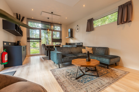 Modern living room and kitchen in Bosrand Wellness Cabin Premium at Vakantiepark De Wiltzangh, Netherlands.