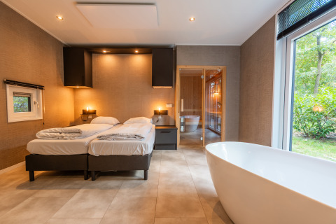 Cabina Bosrand Wellness Premium con due letti e vasca da bagno indipendente nel parco De Wiltzangh, Olanda.