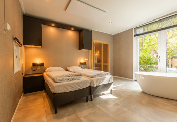 Camera moderna nella Bosrand Wellness Cabin Premium con vasca da bagno, sauna e vista sulla natura.