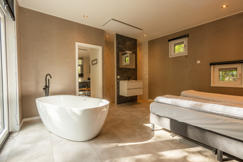 Moderne wellness cabin met losstaand bad en tweepersoonsbed in Vakantiepark De Wiltzangh, Nederland.