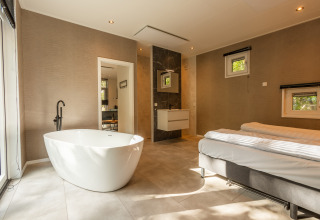 Moderne wellness-hytte med fritstående badekar og dobbeltseng på Vakantiepark De Wiltzangh, Holland.