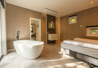 Moderne wellness-hytte med fritstående badekar og dobbeltseng på Vakantiepark De Wiltzangh, Holland.