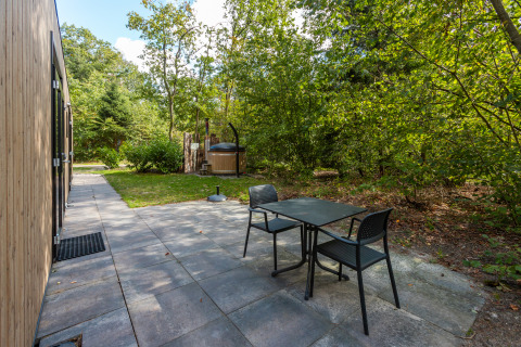 Terras van Bosrand Wellness Cabin Premium met tafel, stoelen en hottub bij De Wiltzangh in Nederland.