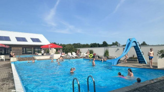 Udendørs swimmingpool med vandrutsjebane og gæster i Hvalpsund Familie Camping, Nordjylland, Danmark.