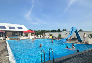 Piscina al aire libre con tobogán de agua y visitantes en Hvalpsund Familie Camping, Jutlandia del Norte, Dinamarca.