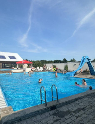 Piscina al aire libre con tobogán de agua y visitantes en Hvalpsund Familie Camping, Jutlandia del Norte, Dinamarca.