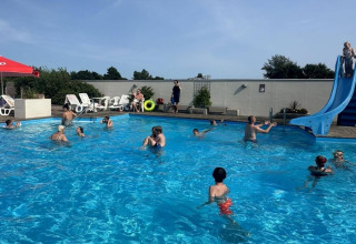 Gezinnen en kinderen genieten van een zonnige dag bij het zwembad van Hvalpsund Familie Camping in Denemarken.