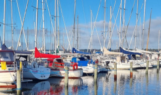 Både og sejlbåde fortøjet ved en småbådshavn nær Farsø, Nordjylland, Danmark på en solrig dag.