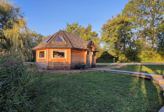 Cabaña de madera en Domaine des Feuilles, parque vacacional en Auvergne-Rhône-Alpes, Francia, rodeada de árboles